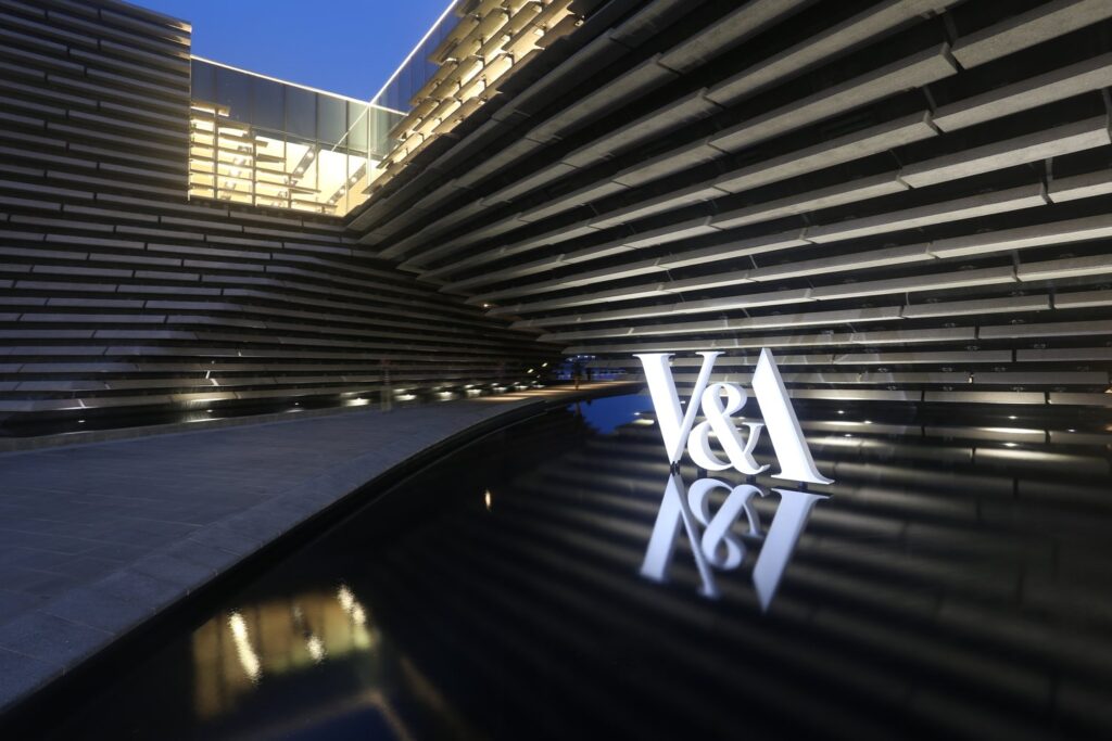 V&A Museum Dundee external built up text signage. white 3 dimensional letters fitted in a pond in front of the museum building.