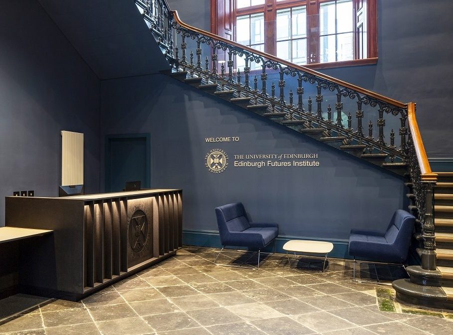 University of Edinburgh Futures Institute flat cut text and crest fitted to an internal blue wall beneath a decorative staircase